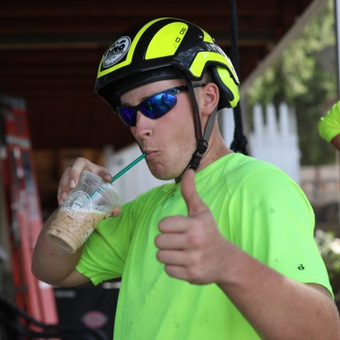 Beaver Dam Tree Service staff Jedidiah Still drinking an iced coffee and giving thumbs-up.